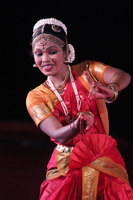 A dancer performs a Bharatnatyam dance at a dance festival, using facial expressions and gestures.