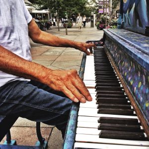 An image of someone sitting at a piano and playing the keyboard with both hands