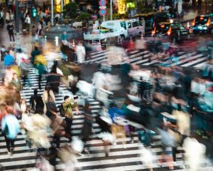 A blurry photo of people crossing a busy intersection.