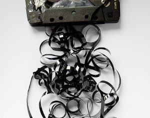 A damaged cassette tape with tape tangled around it.