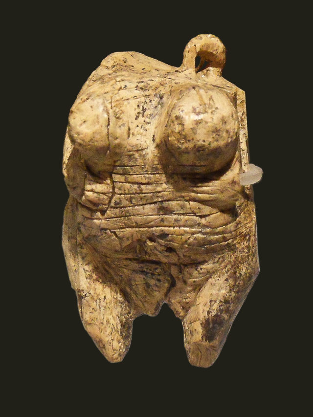 An image of the Venus figurine known as the "Venus of Willendorf," an ancient statuette carved from limestone. The figure is characterized by exaggerated features such as large breasts and a rounded body, often interpreted as a symbol of fertility. The figurine is believed to date back to the Paleolithic period.
