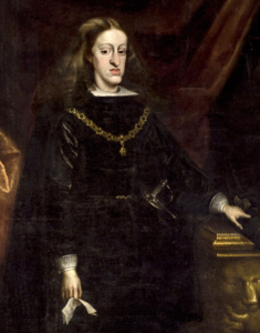 Painted portrait of Charles II of Spain in his twenties, dressed in dark royal attire with a gold chain and standing beside a pedestal.