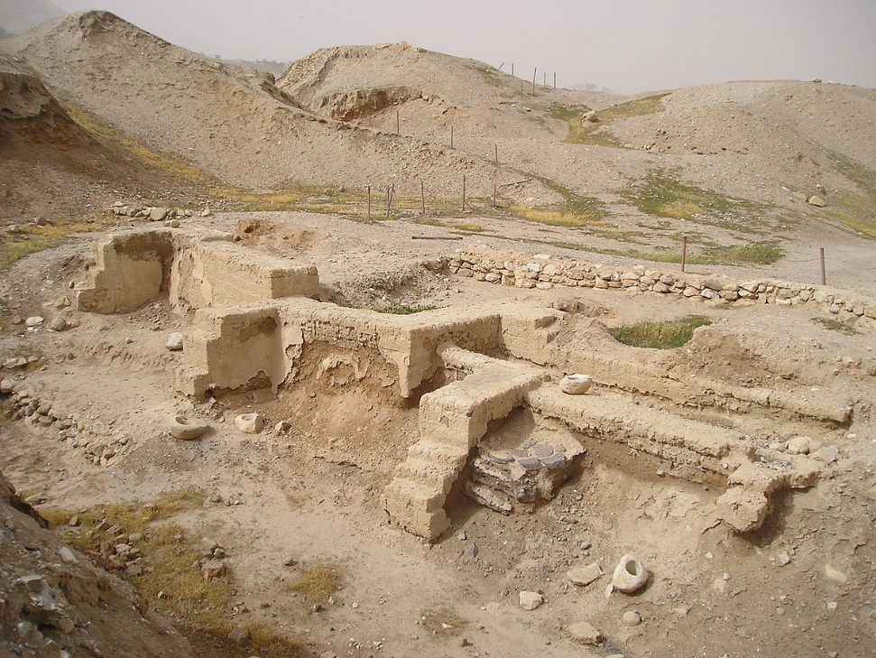Excavated archaeological site at Jericho showing the foundations of ancient mud-brick structures surrounded by desert hills.