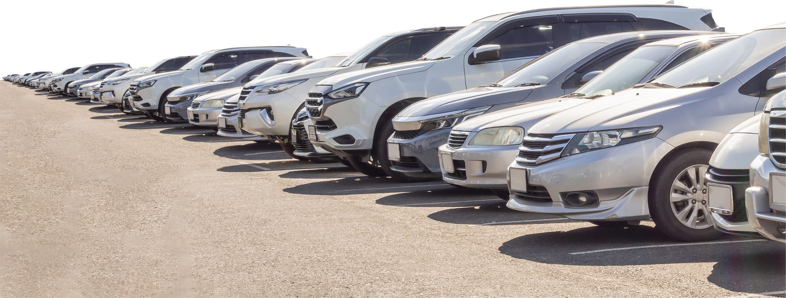 Row of parked vehicles including SUVs, minivans, and sedans in an outdoor parking lot.
