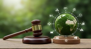 A gavel beside a globe covered in green foliage, surrounded by icons symbolling sustainability and society. Adobe Stock