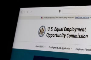 Screenshot of the U.S. Equality Employment Opportunity Commission (EEOC) website, showing the official banner, logo, and navigation menu with sections for employees, employers, and general information. Adobe Stock